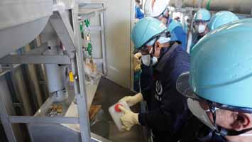 多核種移送設備建屋にて採水している様子（IAEA関係者）