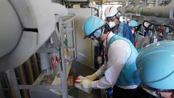 多核種移送設備建屋にて採水している様子（スイスの分析機関関係者）
