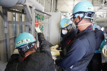 多核種移送設備建屋にて採水している様子（IAEA関係者）