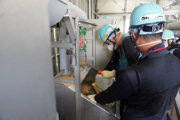 多核種移送設備建屋にて採水している様子（スイスの分析機関関係者）