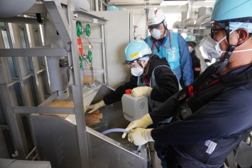 多核種移送設備建屋にて採水している様子（ロシアの分析機関関係者）