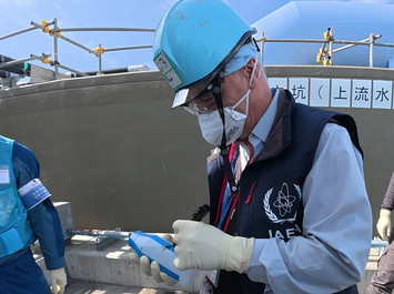採取したALPS処理水に署名をするIAEA関係者