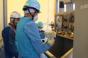 希釈・放出設備にて採水している様子（スイスの分析機関関係者）